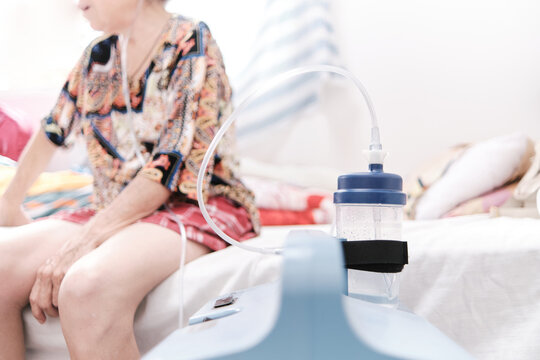 oxygen machine in front of female patient in bed