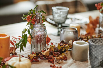 Close-up of dining table with beautiful service on it decorated with autumn branches