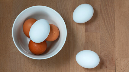 several fresh chicken eggs in a ceramic cup on a wooden background. Healthy eating concept