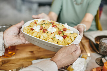 Close-up of man serving hot dinner for his family at dining table