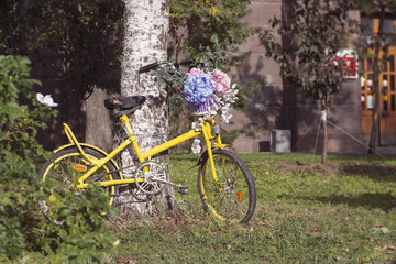 Fototapeta premium Yellow old bicycle with basket filled with flowers