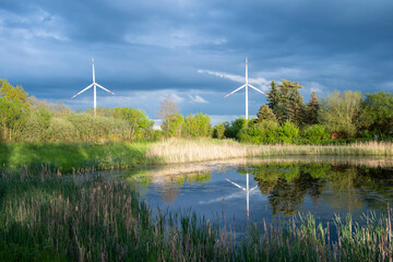 2 Windräder spiegeln sich in einem Weiher in Wangelau