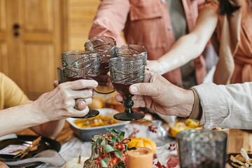 Close-up of family toasting glasses with red wine during family dinner