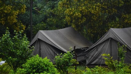 Gray camping tents in nature covered with trees on background. Time spending on fresh air. Travelling concept.