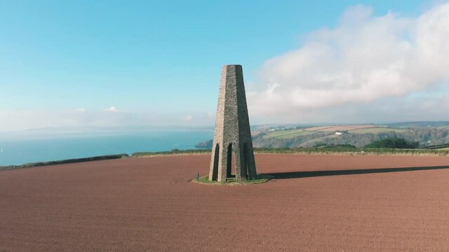 Aerial view of a 19th Century limestone tower The Daymark in a meadow on the coast in Kingswear, Devon, UK
