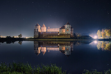 Night Landscape of Mir Castle. Clear night sky with reflections in lake, Belarus.