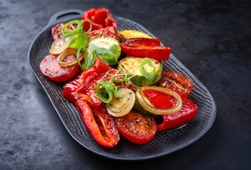 Modern Style traditionelles Grillgemüse mit Zwiebelringen und Kräutern serviert als Beilage auf einem Design Teller