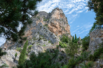 View on mountains cliff, old houses, green valley in remote medieval village Moustiers-Sainte-Marie in Provence, France