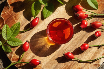 A bowl of rosehip seed oil with fresh rosehips