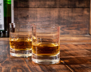 Glasses of strong scotch single malt whisky served on dark wooden table in old pub