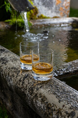 Glasses of strong scotch single malt whisky served on old stone reservoir for water from mountain spring