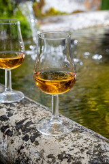 Glasses of strong scotch single malt whisky served on old stone reservoir for water from mountain spring