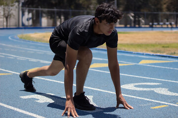 Runner ready in the starting area of a running track, looking straight ahead with determination