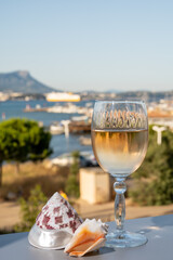 Summer on French Riviera, drinking of cold white or gris rose wine from Cotes de Provence on outdoor terrase with view on harbour of Toulon, Var, France and sea shells
