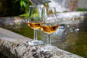 Glasses of strong scotch single malt whisky served on old stone reservoir for water from mountain spring