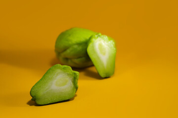 Close-up view of fresh chayote (Sechium edule) isolated on orange background. Also known as...
