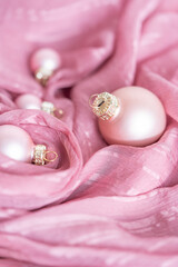 delicate pink Christmas decorations on a pink silk fabric background. The concept of a holiday,...