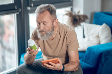 A mature man choosing vitamins and looking involved