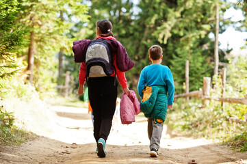 Back of mother with three kids walking on wood mountains. Family travel and hiking with childrens.