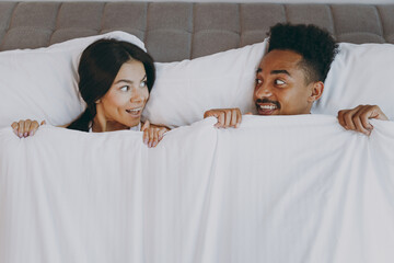 Top view amazed fun young couple two friends family man woman in casual white clothes lying in bed...