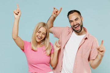 Young cheerful smiling couple two friends family man woman in casual clothes dancing rejoicing together isolated on pastel plain light blue color background studio portrait People lifestyle concept.