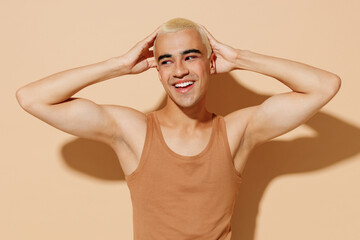 Young happy smiling fun blond latin hispanic gay man 20s with make up in beige tank shirt posing...