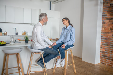 A man and a woman sitting in the kitchen and talking