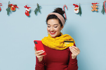 Satisfied young woman 20s years old wear yellow mittens scarf sweater using mobile cell phone hold...