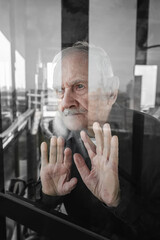 lonely old man looks out of the window, waiting. The concept of loneliness, old age, pandemic...