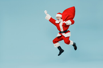 Full body old Santa Claus man 50s in Christmas hat red suit clothes jump like super hero with gifts...