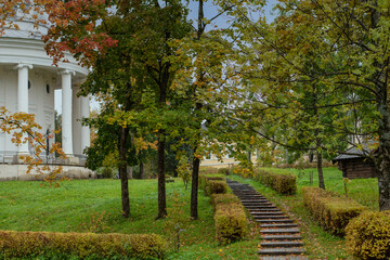 Autumn cityscape, stairs leading to an old building with columns in fallen leaves, colored trees.