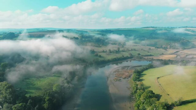 Aerial view of a dreamy misty landscape with winding river and lush green countryside in Sharpham, Devon, UK