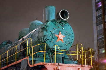 old green steam locomotive close - up at night