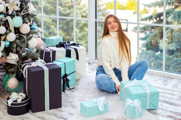 happy young woman with gifts near christmas tree at christmas at home