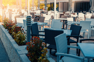white and black tables and chairs made of wicker plastic in an outdoor cafe. During the Covid 19 pandemic, cafe verandas are especially relevant