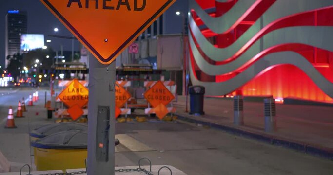 Road Work Ahead sign during metro construction and light transportation traffic at night in Los Angeles, California, 4K