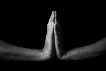Two male hands held out, palms pressed together in thought or prayer.