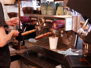 Barista using old espresso machine and pouring coffee into takeaway white cup. hands only. 