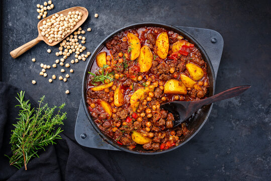 Traditional Italian ceci al sugo chickpeas with salsiccia and minced beef stew with tomato sauce and potato served as top view in a cast-iron skillet