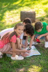 Enthusiastic girl with magnifying glass and friends with map