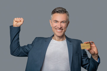 Man with credit card raising his hand victoriously