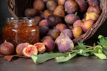 a basket of fresh figs and a jar of fig jam on a dark gray background