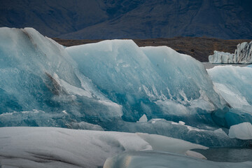 Plakat Icebergs floating. Ices and icebergs. Glacier lagoon. Greenland iceberg. Melting ice. South coast Iceland. Jokullsarlon glacier lagoon. Volcanic ash on the ice. Ice age glacier. Melting iceberg.