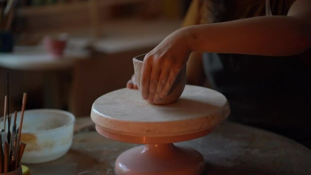 Female potter worker shaping bowl in studio working with raw clay on wheel. Closeup of pottery master creating ceramics handicraft. Small business ownership and craft handmade crockery making concept