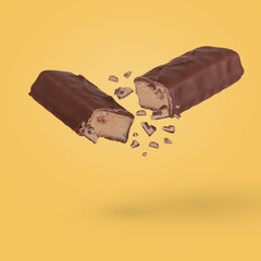 Cracked chocolate bar with milk filling floating in the air isolated on yellow background.
