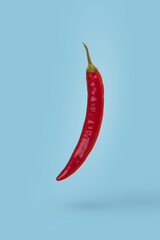 Red hot chili pepper floating in air isolated on blue background