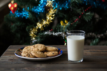 Cookies and a glass of milk on a Christmas tree background.