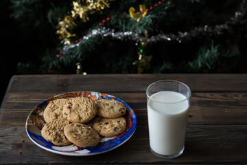 Cookies and a glass of milk on a Christmas tree background.