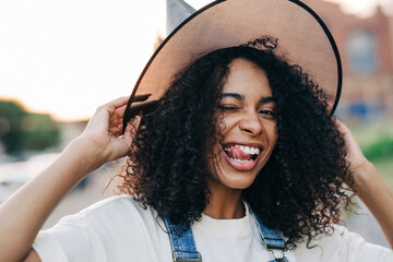 Portrait of young african american woman wearing witch halloween hat grimaces and smile. Lifestyle Halloween concept. - obrazy, fototapety, plakaty