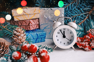 Fototapeta na wymiar Christmas card with an alarm clock and gifts in boxes under the Christmas tree. A ready-made Christmas and New Year greeting card